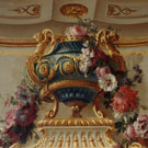 Panel painting of an elaborate porcelain vessel decorated with flowers. 