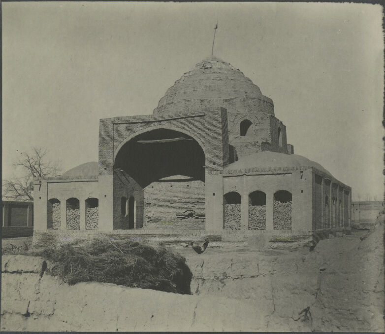 Black and white photograph of a domed brick building constructed on a square plan with a large arch in front.