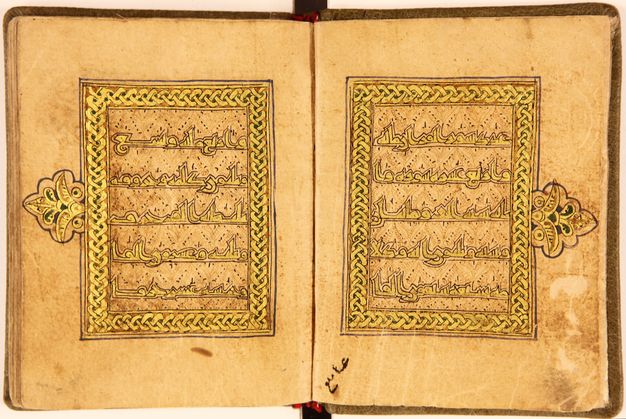 Manuscript spread showing two golden braided frames, each with medallions and containing five lines of golden Arabic script.