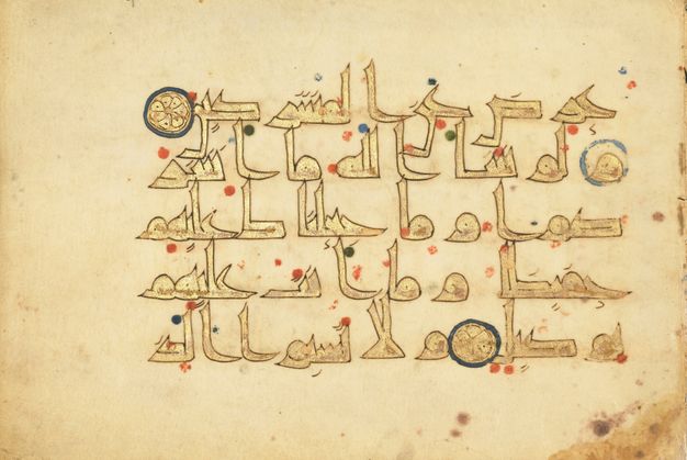 Page with five lines of golden Arabic text; red, green, and blue dots; and two golden rosettes.