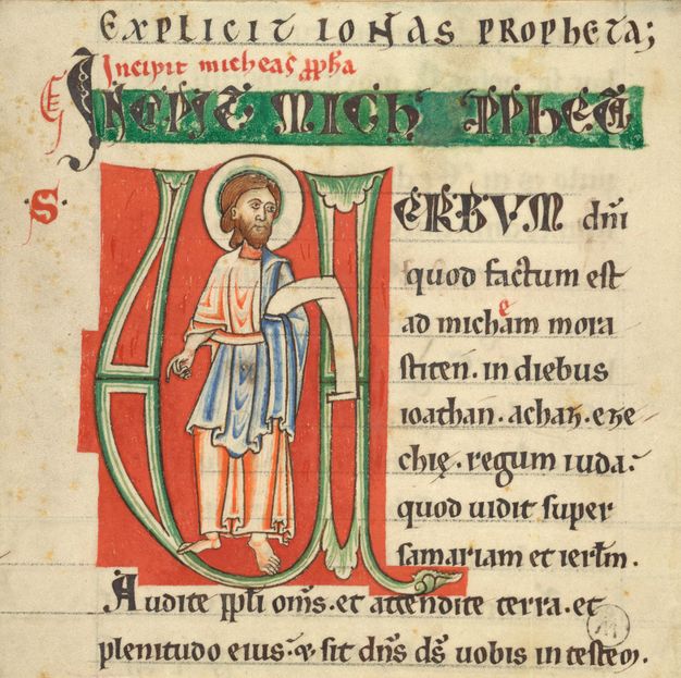A robed man with halo, standing within a large initial.