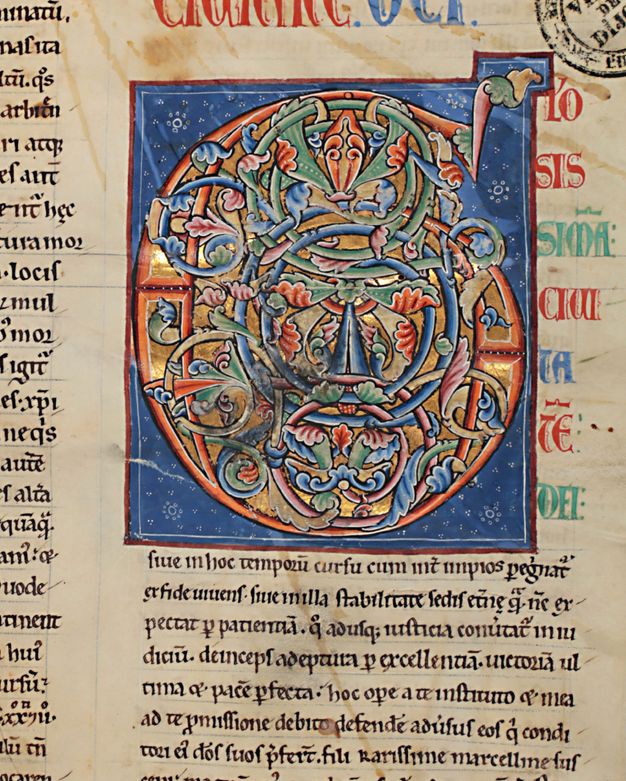 Initial filled with burnished gold and blue, green, and orange-red foliate ornament within a blue background.