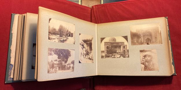 Viewed from above, a three-dimensional album open to a double-page spread of landscape-oriented pages, each with three sepia-toned photographs.