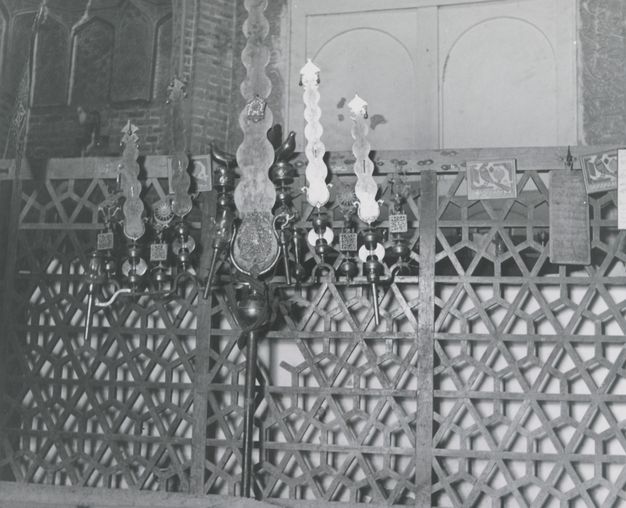 Black and white photograph of a geometric wood screen with items attached to it.