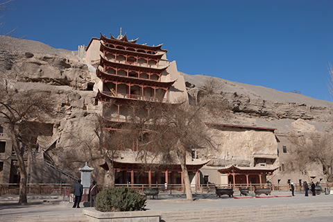 Exterior view of the cliff face at Dunhuang, showing the nine-story temple and a group of visitors