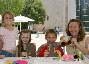 Kids and adults proudly displaying their work at an art-making workshop