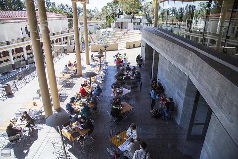 On a sunny and clear day, people eat lunch at the tables on the terrace outside the Cafe at the Getty Villa.