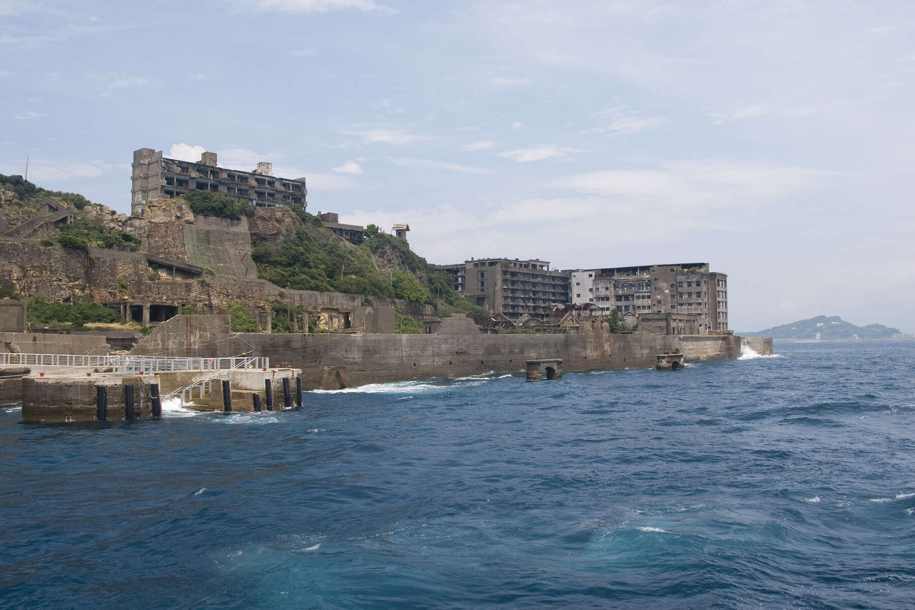 Abandoned island with concrete ruins of a mining facility, undisturbed except by nature and the surrounding sea wall.