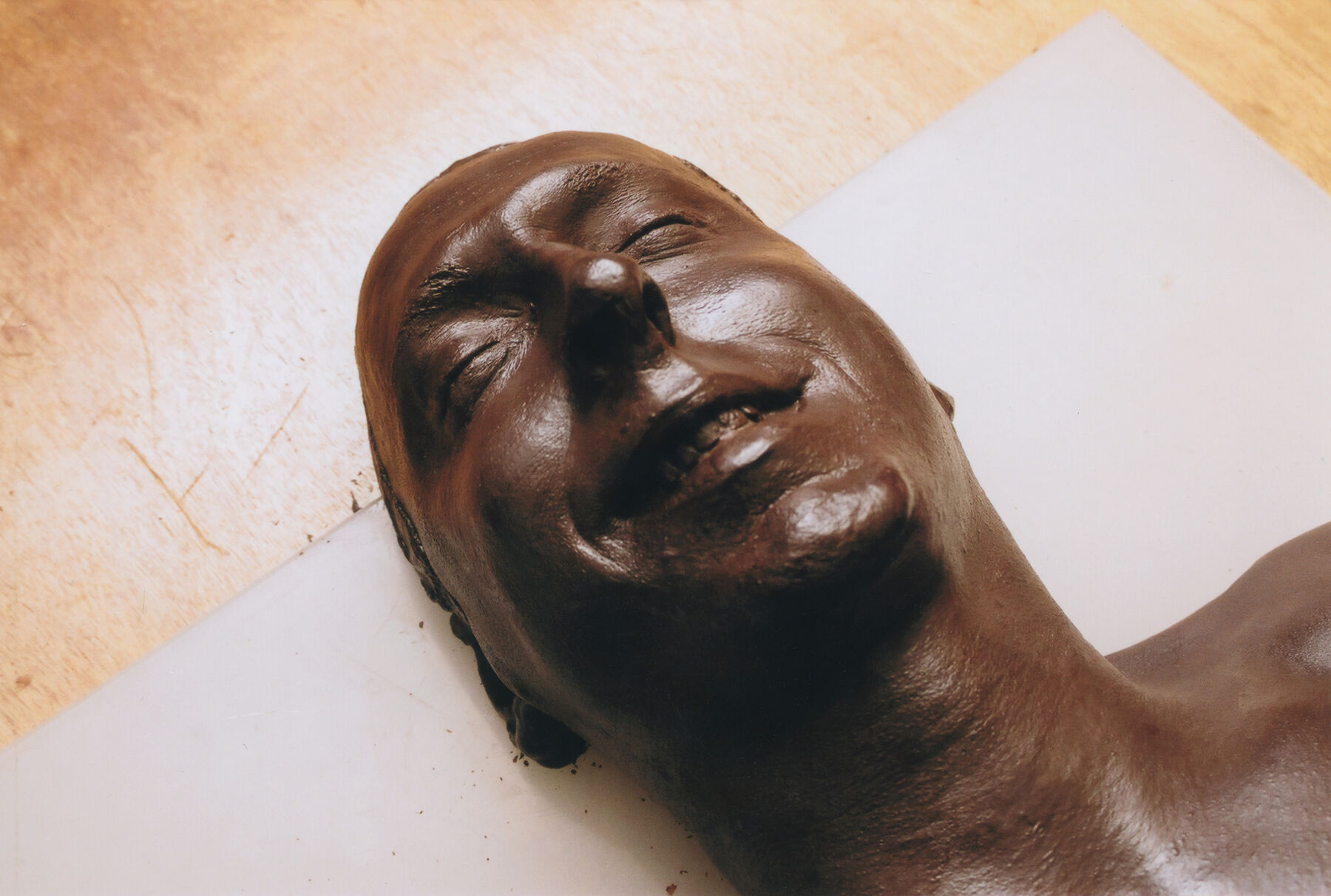 Artist Laurent Moriceau smiling while being covered by chocolate as he is laying down on the floor