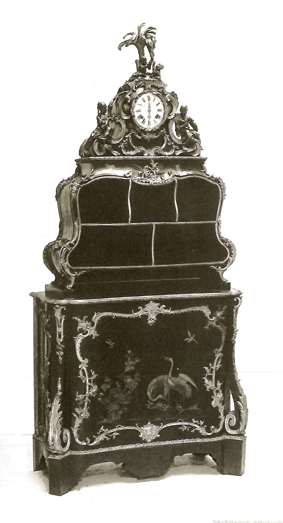 three-quarter view of the cartonnier as photographed in the 1920s, revealing the additional floral gilt bronze mount added to the center of the bout de bureau as well as the absence of a palm tree from the mount on the top of the clock