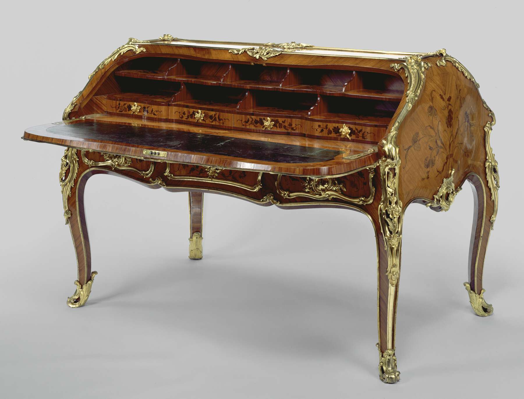 three-quarter view of the desk with one side open, revealing a flat writing surface decorated with dark leather, four small drawers, and nine pigeonholes