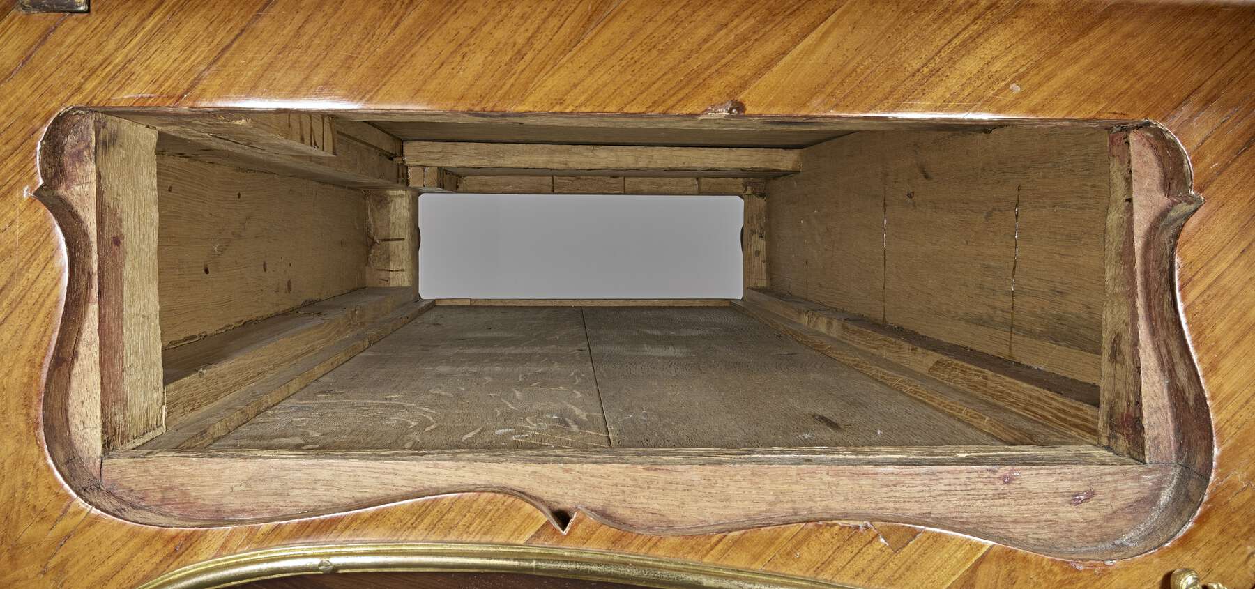 interior view of the desk, showing a glossy finished wood on the outside and a rougher unfinished interior made up of multiple wooden strips