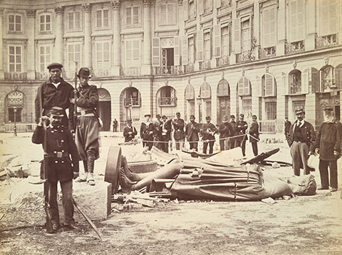 A black-and-white photograph of soldiers standing around a recently toppled statue of Napoleon. 