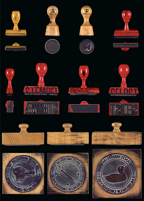 Bottom and side views of eleven of Harald Szeeman's rubber stamps are arranged in three rows.