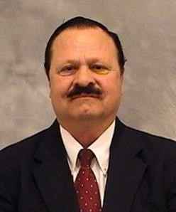 Carlos Rodriguez wears a dark suit jacket over a white collared shirt and red tie